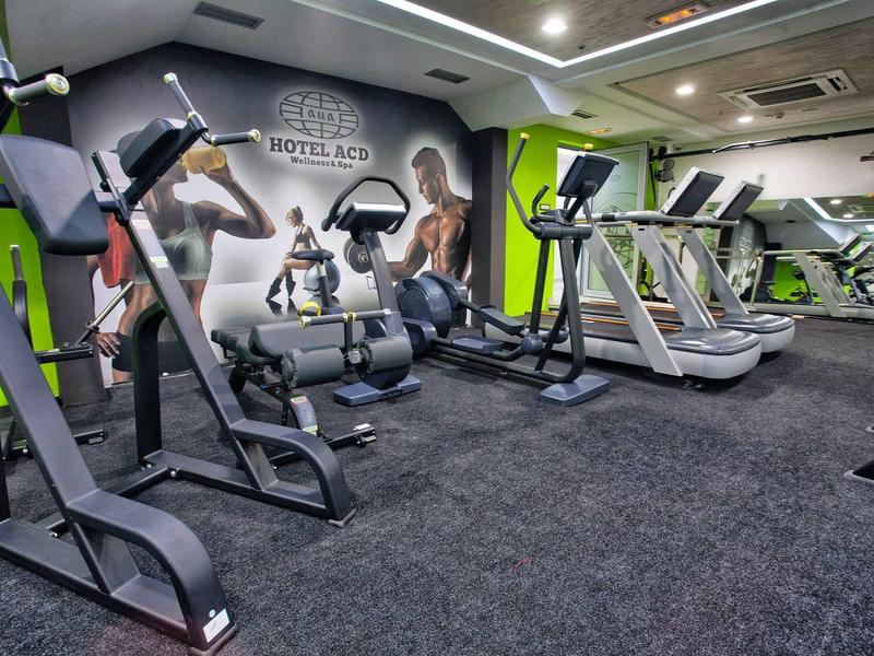 Modernes Fitnessstudio mit Laufbändern, Kraftgeräten und grünen Akzentwänden.