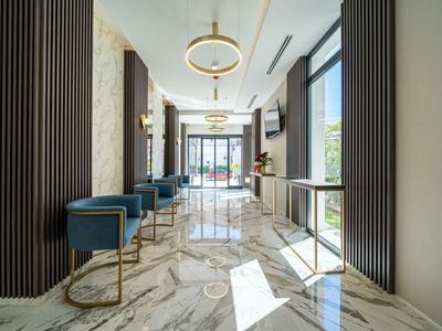 Moderner Flur mit weißem Marmorboden, blauen Sesseln und goldfarbenen Akzenten, helle Beleuchtung.