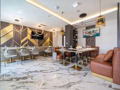 Moderner Essbereich mit Marmorboden, braunen Sesseln, Metalltischen und geometrischer Wandgestaltung.