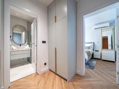 Moderní hotelová chodba s přístupem do koupelny a ložnice, dobře osvětlená, čistá a světlá.