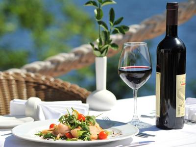 Elegantes Tischarrangement mit Wein, Glas und Teller mit Salat auf einer Terrasse.