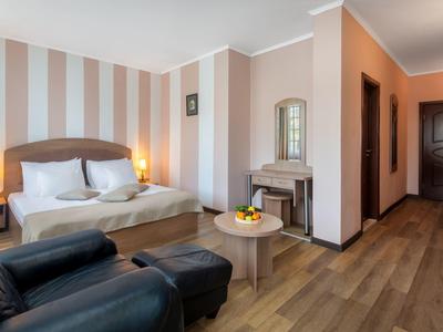 Hotelzimmer mit Doppelbett, Sessel, Tisch mit Obst und Holzboden.