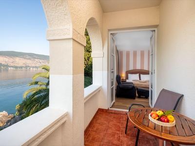 Balkon mit Blick auf das Meer, kleiner Tisch mit Obst und zwei Stühlen.
