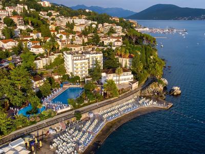 Küstenstadt mit Hotels, Pool und Strandabschnitt am Meer unter klarem Himmel.