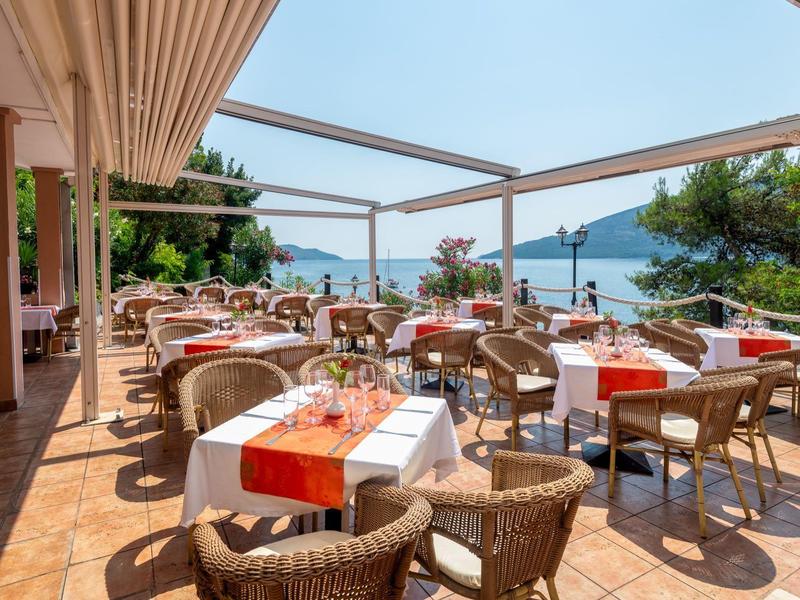 Große Außenterrasse eines Hotels mit gedeckten Tischen und Blick aufs Meer.