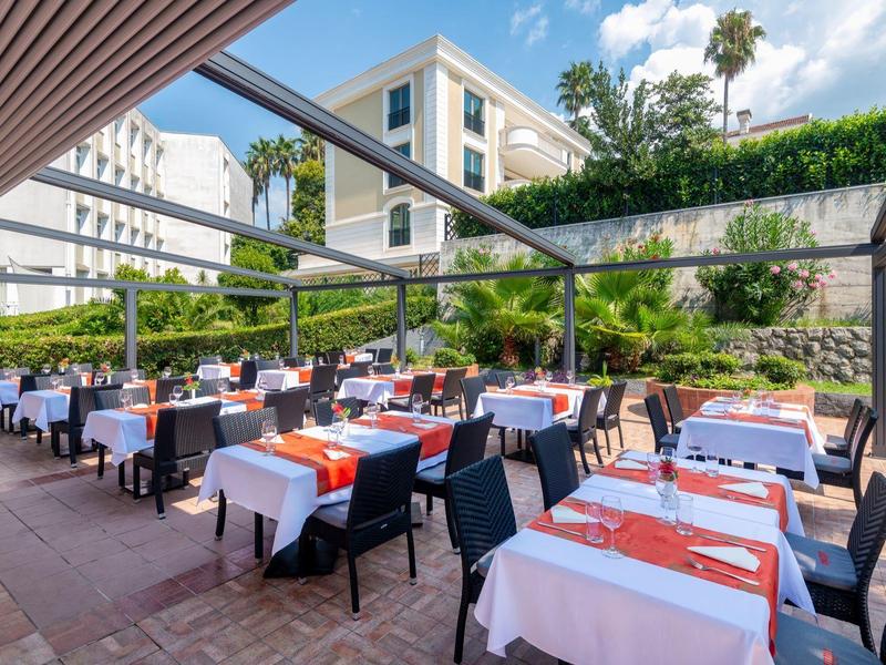 Outdoor-Restaurantterrasse mit gedeckten Tischen und Stühlen bei Tageslicht