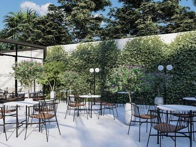 Área exterior moderna con mesas y sillas negras frente a una pared verde y árboles.