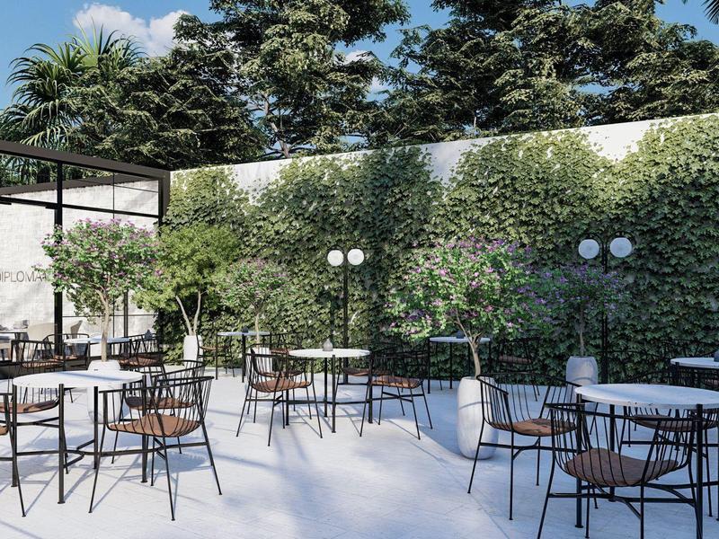 Heller Außenbereich mit weißen Stühlen, schwarzen Tischen und grün bewachsener Wand.