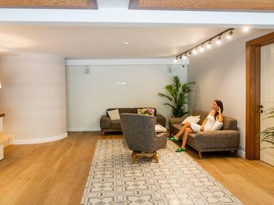 Helles Wohnzimmer mit Holzboden, zwei grauen Sofas, Teppich und grünen Zimmerpflanzen.