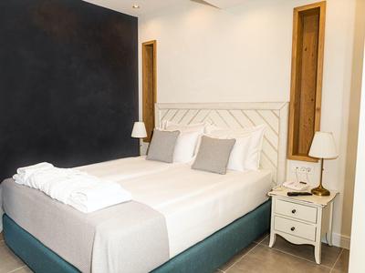 Modernes Schlafzimmer mit weißem Bett, grauen Kissen, Nachttisch und zwei Lampen.