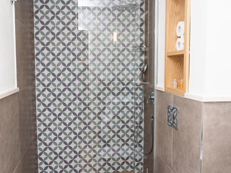 Moderner Badbereich mit gemusterter Glaswand, Wand-WC und offenen Holzregalen.