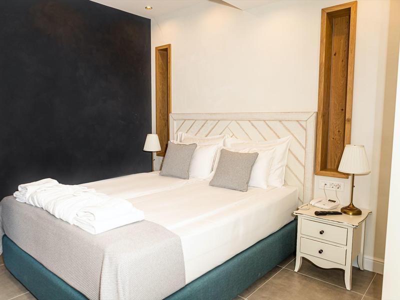 Modernes Schlafzimmer mit weißem Bett, grauen Kissen, Nachttisch und zwei Lampen.