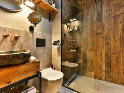 Modernes Badezimmer mit Holzverkleidung, Steinwaschbecken, Toilette und begehbarer Dusche.