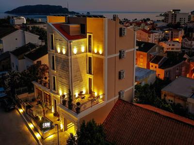 Modernes dreistöckiges Haus in gelbem Licht bei Dämmerung in ruhiger Wohngegend mit umliegenden Gebäuden.