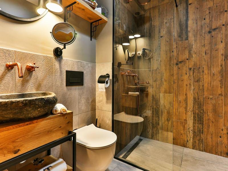 Modernes Badezimmer mit Holzverkleidung, Steinwaschbecken, Toilette und begehbarer Dusche.
