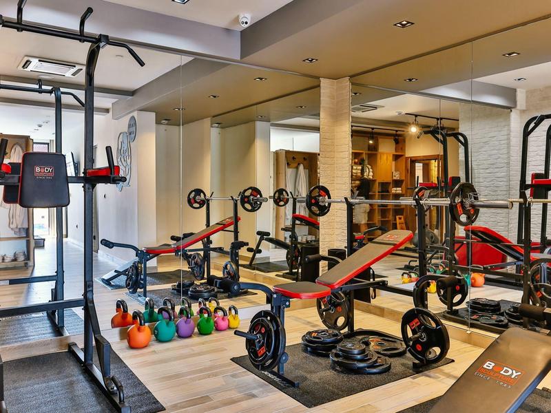 Moderne Fitnessstudio mit Hanteln, Kettlebells und Trainingsgeräten in hellem, großem Raum.