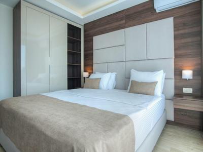 Modernes Schlafzimmer mit großem Bett, eingebautem Schrank und Holzwandpaneelen.