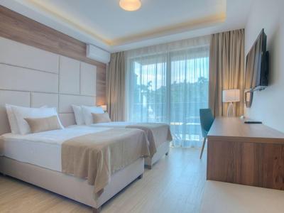 Hell eingerichtetes Hotelzimmer mit zwei Einzelbetten, großem Fenster und modernem Holzmobiliar.