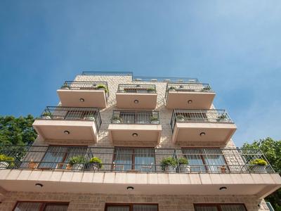 Balcón con sillas y mesa de madera, ventanas de vidrio y plantas en habitación de hotel