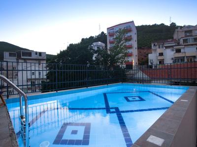 Freier Pool auf Dachterrasse mit Metallgeländer und umliegenden Gebäuden bei Dämmerung.