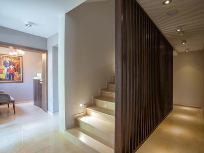 Moderner Innenraum mit Treppe, dunklen Holzleisten und hellem Boden im warmen Licht.