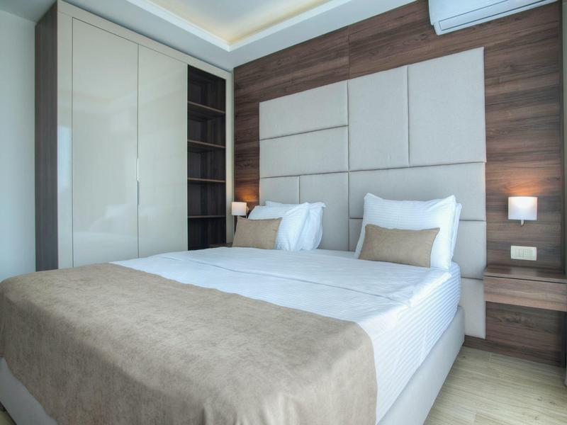 Modernes Schlafzimmer mit großem Bett, eingebautem Schrank und Holzwandpaneelen.