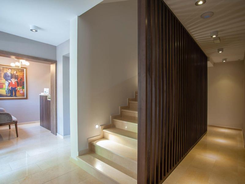 Moderner Innenraum mit Treppe, dunklen Holzleisten und hellem Boden im warmen Licht.