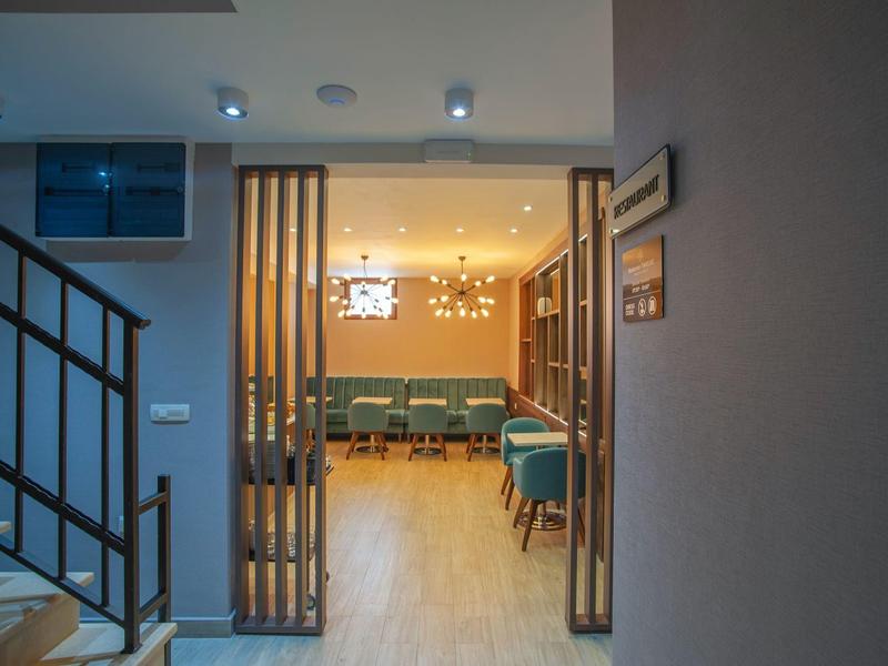 Moderner Innenraum mit Holzfußboden, gemütlichen Sitzbereichen und warmem Deckenlicht.