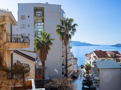 Vista sul mare tra edifici con palme sotto un cielo sereno