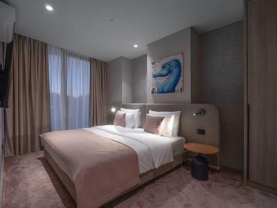 Modernes Schlafzimmer mit großem Bett, brauner Bettdecke, grauen Wänden und gemaltem Wellenbild.