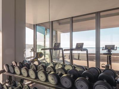 Palestra con ampia gamma di manubri davanti a grandi finestre con vista mare.