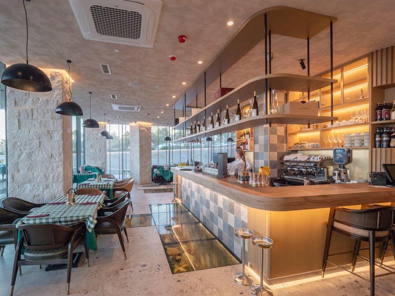 Moderner Café-Innenraum mit Holztheke, schwarzen Stühlen und großen Pendelleuchten.