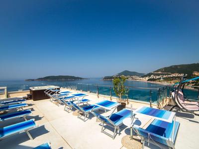 Dachterrasse mit blauen Liegestühlen, Meerblick und klarem Himmel am sonnigen Tag.