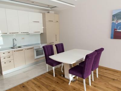 Zona pranzo moderna con sedie viola e tavolo bianco accanto a un angolo cottura