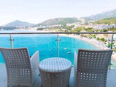 Due sedie e un tavolo su un balcone con vista su una spiaggia e il mare.