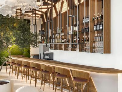 Nowoczesny bar hotelowy z długimi drewnianymi ladami, krzesłami i dekoracyjnym oświetleniem sufitowym.