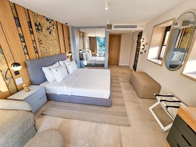 Nowoczesny pokój hotelowy z łóżkiem podwójnym, częścią wypoczynkową i drewnianą dekoracyjną ścianą.