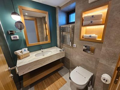 Kompaktowa łazienka hotelowa z umywalką, podświetlanym lustrem, toaletą i grzejnikiem na ręczniki.