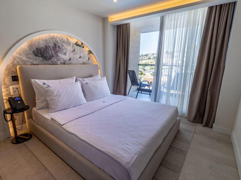 Nowoczesny pokój hotelowy z łóżkiem podwójnym, balkonem i widokiem na miasto