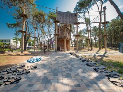 Ein Kletterparcours im Freien in einem Park mit Bäumen und gepflastertem Weg.