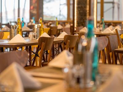 Elegantes Restaurant mit gedeckten Tischen und Holzmöbeln in warmem Licht.