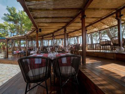 Überdachte Terrasse mit gedeckten Tischen und Stühlen in einem Restaurant nahe Bäumen.