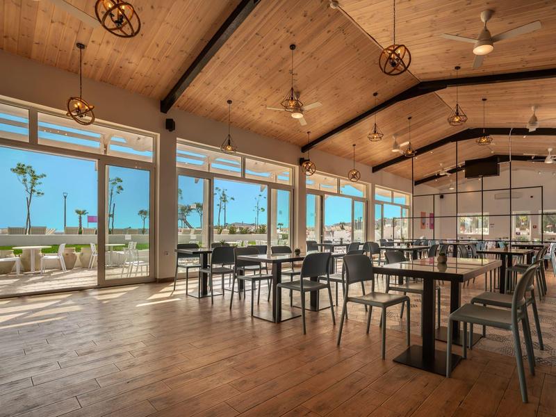 Prostorný, světlý jídelní prostor s dřevěnou podlahou a velkými okny s výhledem na terasu.