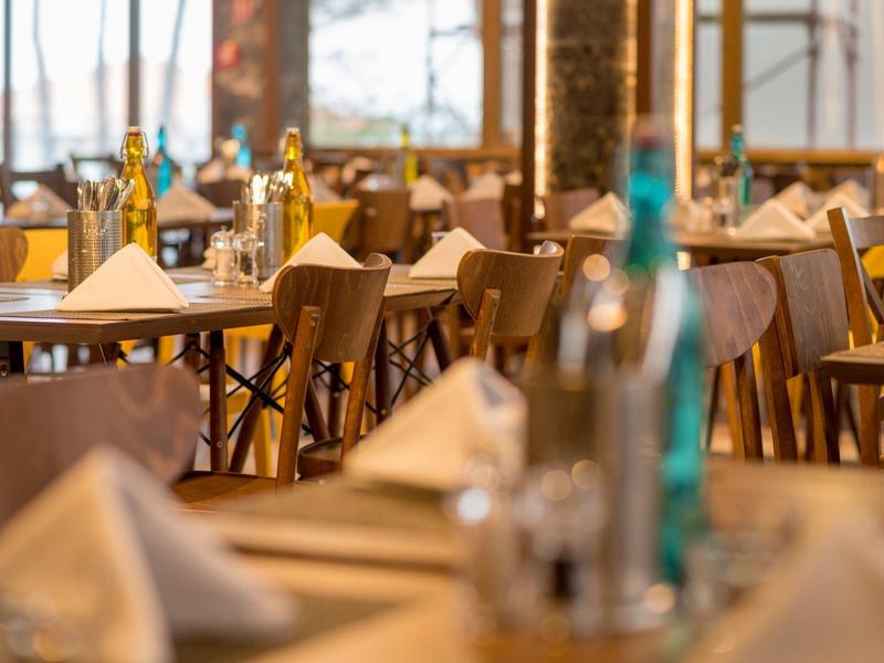 Elegantní restaurace se stylově prostřenými stoly, dřevěnými židlemi a lahvemi na stolech.