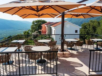 Terraza al aire libre con mesas y sillas bajo sombrillas con vista a las montañas.