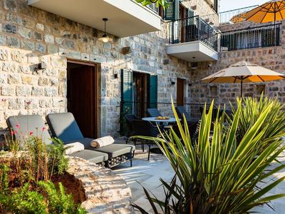 Gemauerte Terrasse mit Liegestühlen, blühenden Pflanzen und Sonnenschirmen bei Sonnenschein.
