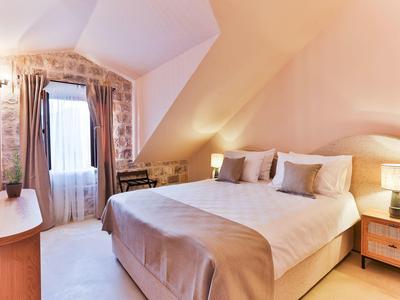 Gemütliches Schlafzimmer mit schräger Decke, Doppelbett, Nachttischen und warmem Licht.