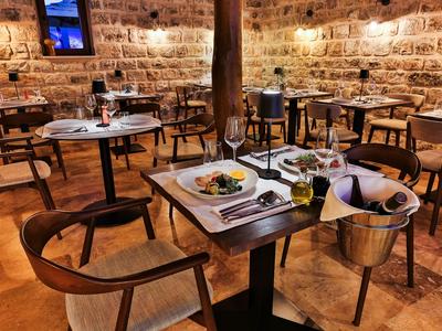 Restaurante acogedor con muebles de madera y paredes de piedra, mesas preparadas y botellas de vino.