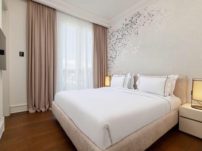 Modernes Schlafzimmer mit großem Bett, weißen Wänden, Holzfußboden und zwei Nachttischlampen.