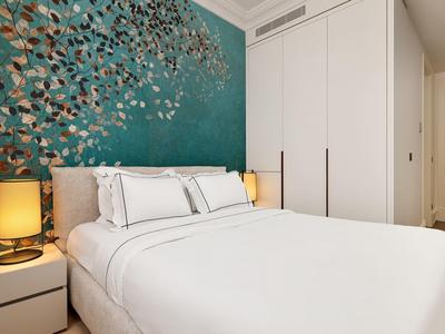 Schlafzimmer mit großem weißen Bett, Nachttischen mit Lampen und Blumentapete in Blau und Gold.